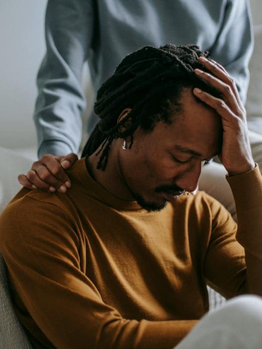 sorrowful black man touching head in dismay near supporting wife