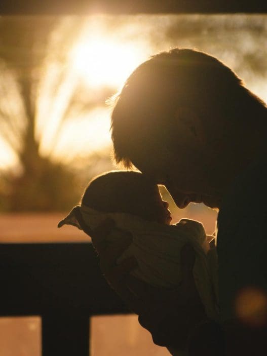 man carrying baby drawing their foreheads
