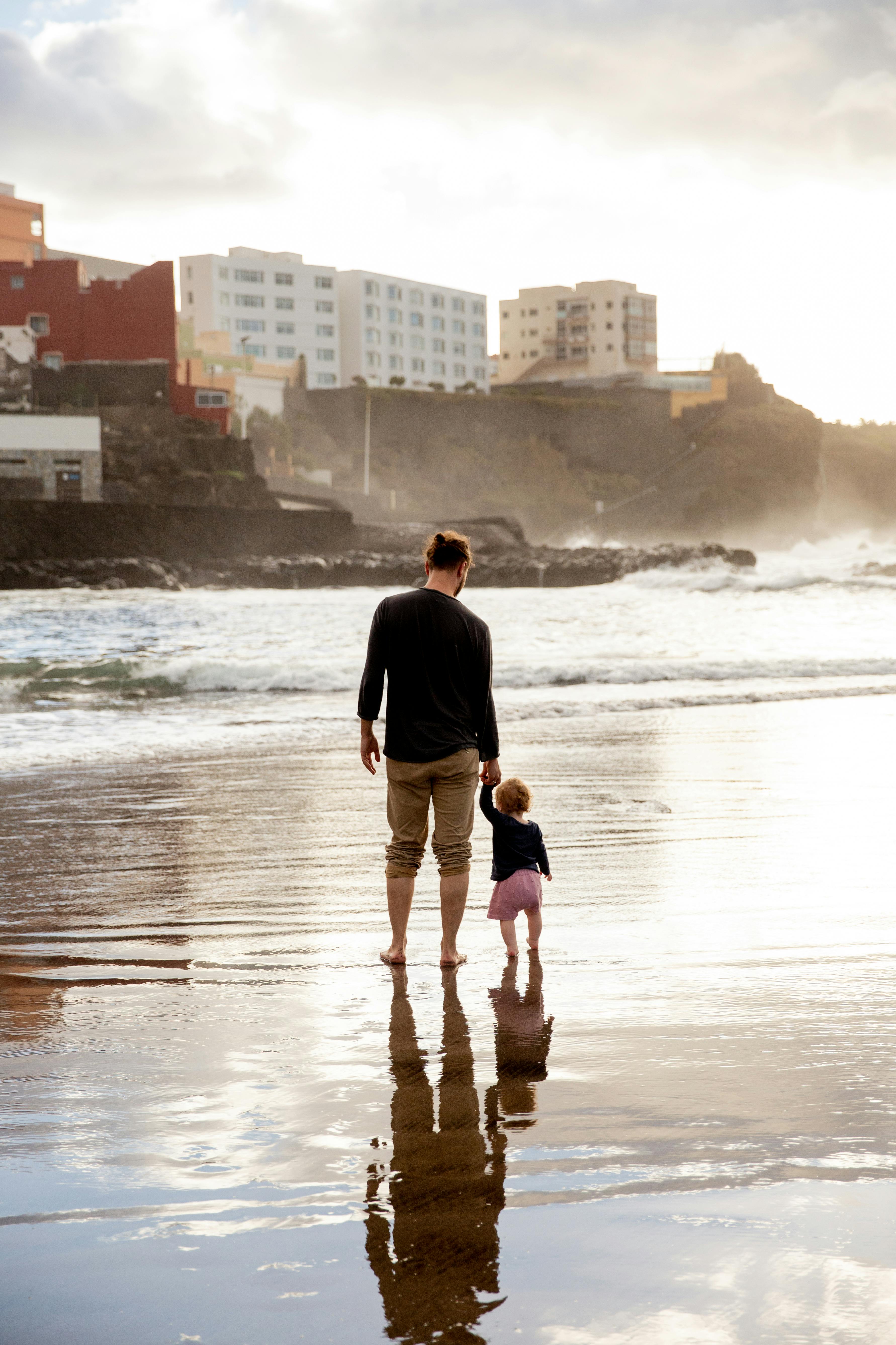 father and child walking on the sand