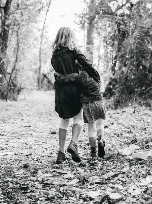 woman walking on pathway between green trees