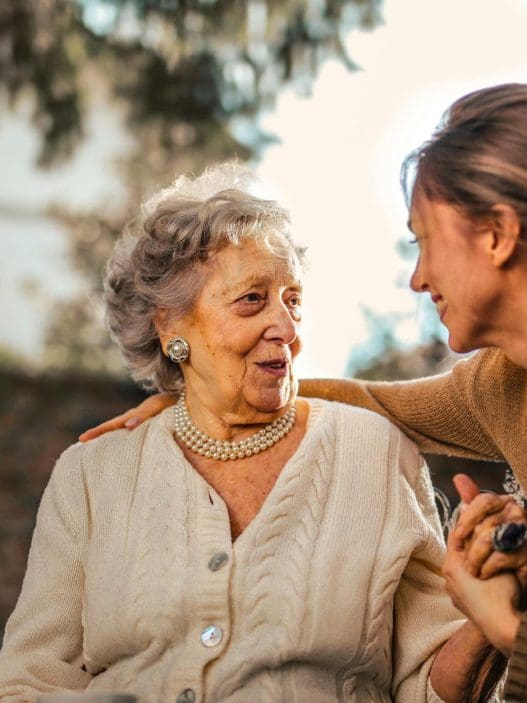 joyful adult daughter greeting happy surprised senior mother in garden