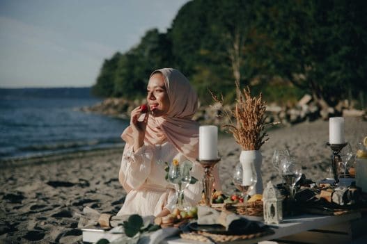 a woman wearing a hijab having a picnic at the beach