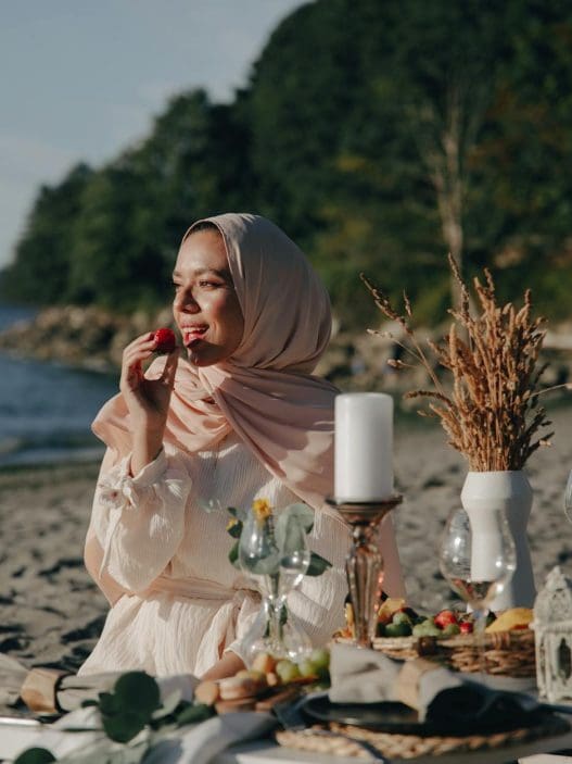 a woman wearing a hijab having a picnic at the beach
