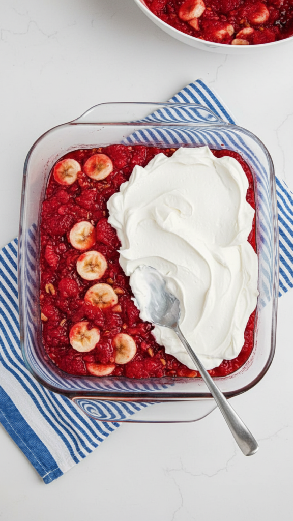 cream being added to the top of a Strawberry Jello Salad