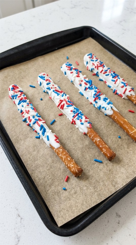 Patriotic Dipped Pretzel Rods on parchment paper on baking tray